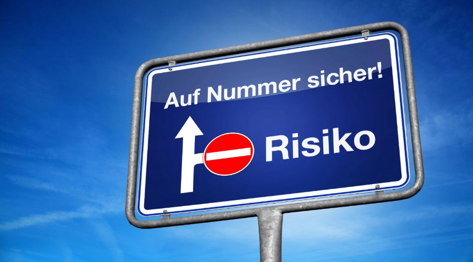 Ein blaues Verkehrsschild mit der Aufschrift „Auf Nummer sicher!“ und „Risiko“, wobei der Weg zum Risiko durch ein Verbotsschild blockiert ist. Ein blaues Verkehrsschild mit der Aufschrift „Auf Nummer sicher!“ und „Risiko“, wobei der Weg zum Risiko durch ein Verbotsschild blockiert ist.